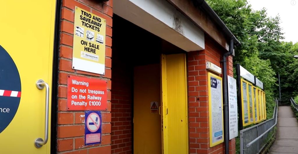 Halewood railway station booking office brick built on the road below the  railway station.